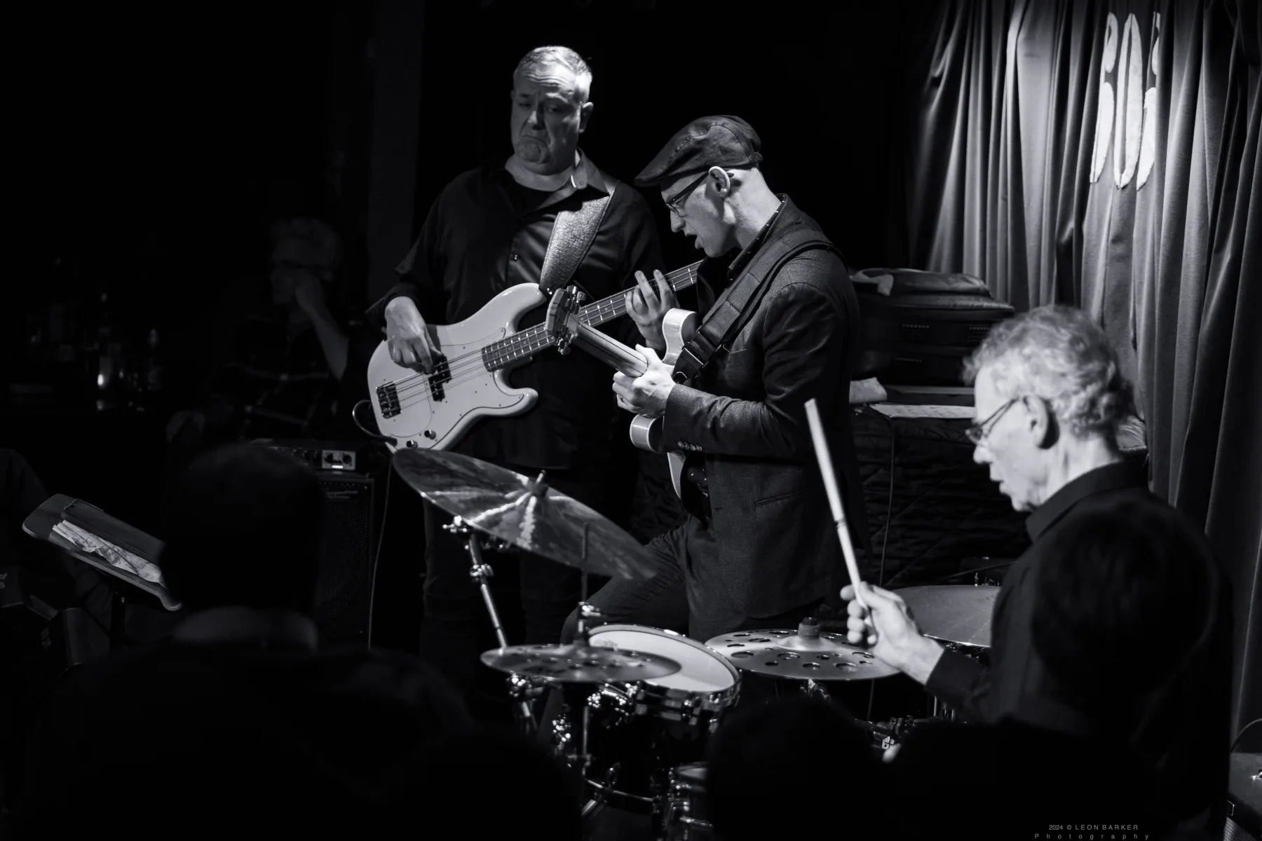 Pete Roth Trio performing in warm red and violet stage light.